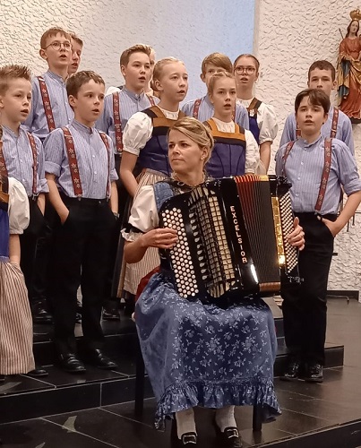 Kinder singend hinter 
				Akkordeonspielerin